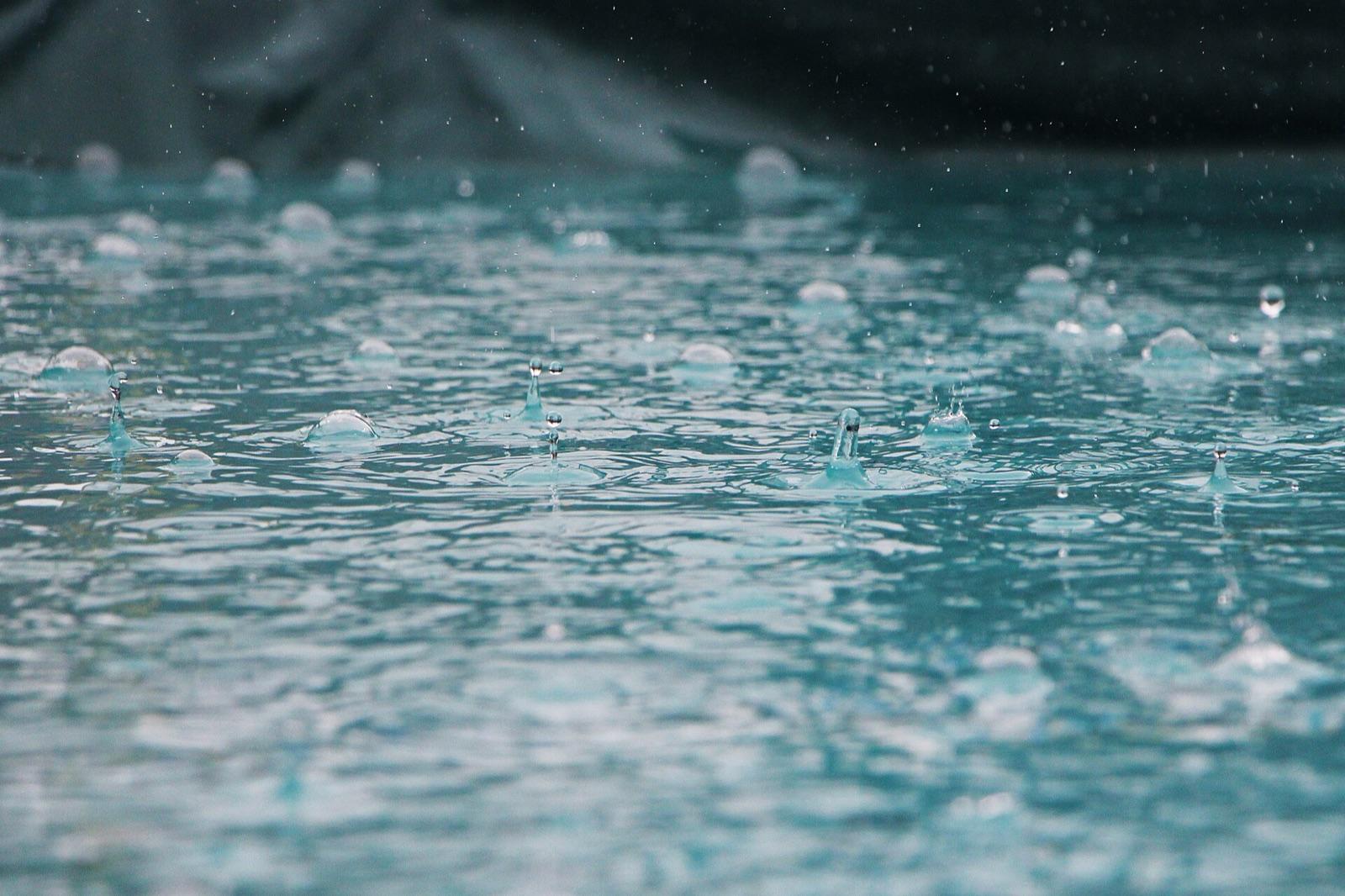 Heavy raindrops splashing into a pool of collected water